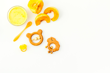 Healthy food for little baby. Puree with pumpkin near pacifier and toys on white background top view.の写真素材