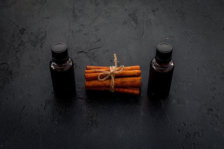 Cinnamon oil for cooking, aromatherapy, skin care. Bottles near cinnamon sticks on black background.の写真素材