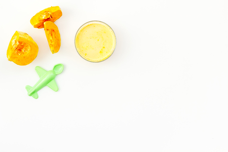 Healthy food for little baby. Puree with pumpkin near toys on white background top view copy spaceの写真素材
