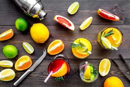 Mix exotic fruit cocktail with alcohol. Shaker and strainer near citrus fruits and glass with cocktail on dark wooden background top view.の写真素材