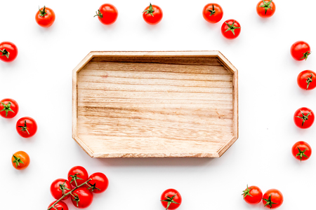 Fresh red cherry tomatoes near wooden tray on white background top view.の写真素材