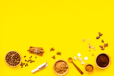 Ingredients for bakery and desserts. Cinnamon, cocoa, coffee, sugar, spices on yellow background top...