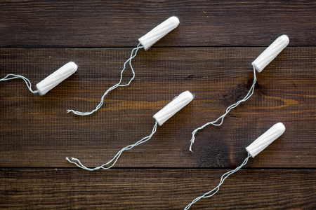 Woman hygiene protection. Cotton tampons like sperms on dark wooden background top view.の写真素材