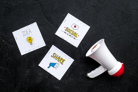 Social media announcements concept. Megaphone near social media icons on black background top viewの写真素材