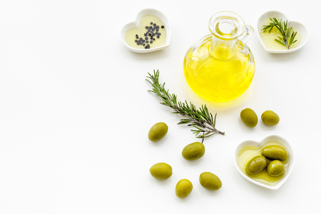 Fresh olive oil in glass jar near green olives and branch of rosemary on white background top view copy spaceの写真素材