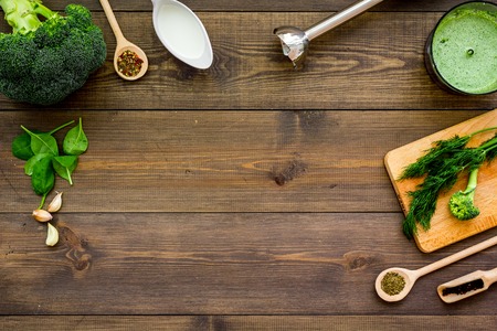 Cook green cream soup with vegetables. Broccoli, cream, spices, blender on dark wooden table top view copy spaceの写真素材