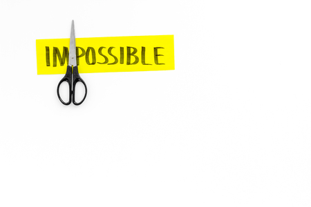 All is possible concept. Cutting the part 'im' of written word impossible by scissor. White background top view copy spaceの写真素材