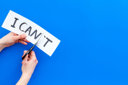 Self confidence concept. Cutting the letter 't' of written word I cant by scissor. Blue background...