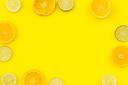 Oranges and lime round slices pattern on yellow background top view.の写真素材