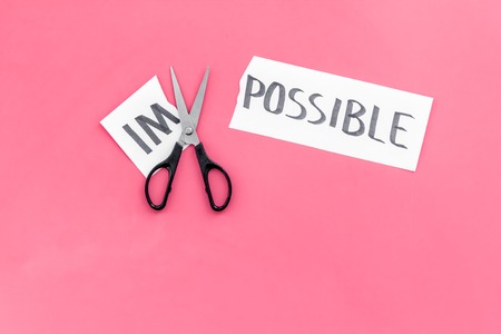 Belief in yourself concept. Cutting the part im of written word impossible by scissors. Pink background top view.の写真素材