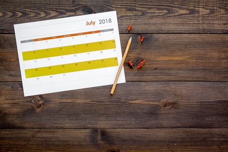 Planning. Point the date in calendar by pushpin. Set the goal. Choose date. Calendar on dark wooden background top view copy spaceの写真素材