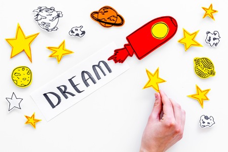 Dream concept. Hand lettering dream at white cosmos background with rocket and stars top view copy spaceの写真素材