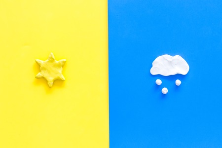 Good and bad weather concept. Template for forecast. Sun vs snow cloud on yellow and blue background top view copy spaceの写真素材