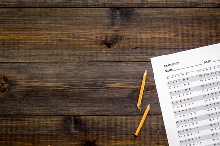 Exam sheet on dark wooden table top view copy space. Education concept. Exam problems. Broken pencil near exam sheet