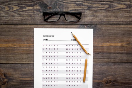 Exam sheet on dark wooden table top view copy space. Education concept. Exam problems. Broken pencil near exam sheet.の写真素材