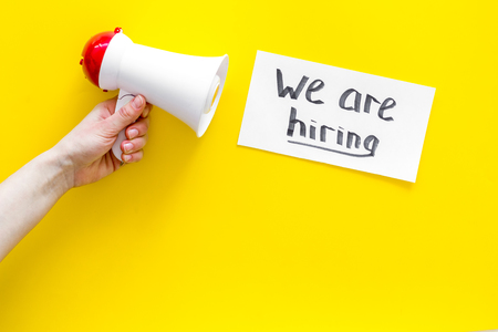 Job recruiting advertisement. We are hiring lettering near megaphone on yellow background top view.の写真素材