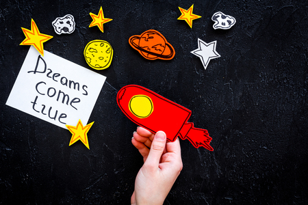 Motivational poster. Dreams come true hand lettering at black cosmos background with rocket and stars top view.の写真素材