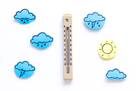 Weather forecast concept. Air temperature. Thermometer among cloud and lightening, sun, rainy clouds on white background top view.の写真素材
