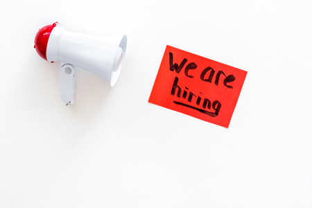 Job recruiting advertisement. We are hiring lettering near megaphone on white background top view copy spaceの写真素材