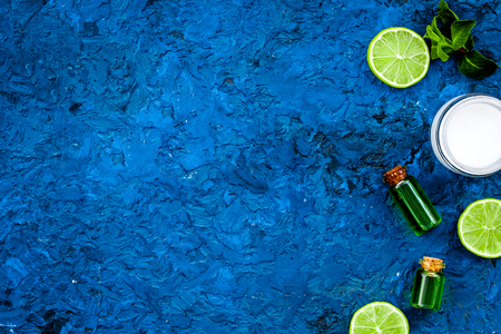 Organic citrus cosmetics for skin care. Lemon or lime oil and moisturising cream on blue background top view copy spaceの写真素材