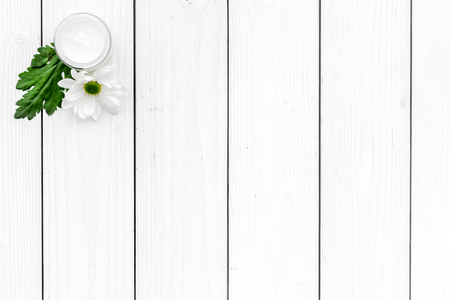 Moisturizing cream based of natural herbal ingredients. Chamomile cream in small jar near chamomile flowers on white background top view copy spaceの写真素材