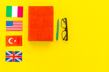 Language study concept. Textbooks or dictionaries of foreign language near flags on yellow background top view copy spaceの写真素材