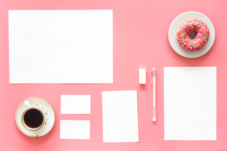 Come up with brand identity. Blank stationery for branding near coffee and donut on pink background top view mockup patternの写真素材