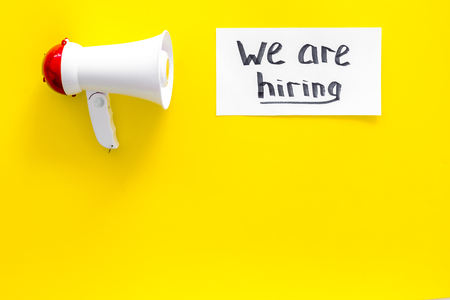 Job recruiting advertisement. We are hiring lettering near megaphone on yellow background top view copy spaceの写真素材
