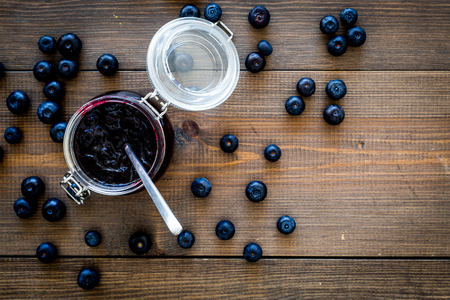 Canned berries. Blueberry jam in glass jar on dark wooden background top view copy spaceの写真素材