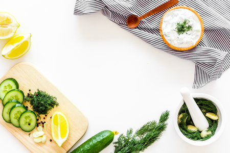Greek yogurt as salad dressing. Bowl with yogurt, greenery, cucumber, oranges on white kitchen desk top view.の写真素材