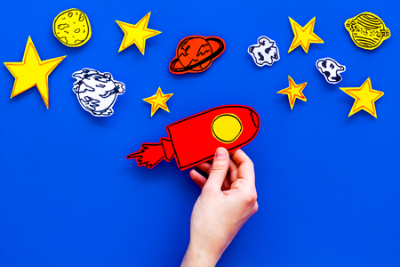 Space tourism concept. Hand hold drawn rocket or spaceship near stars on blue background top view.の写真素材