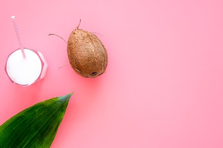 Light cocktail with coconut milk. White tropical beverage in glasses with straw on pink background with coconut and palm leaves top view.の写真素材