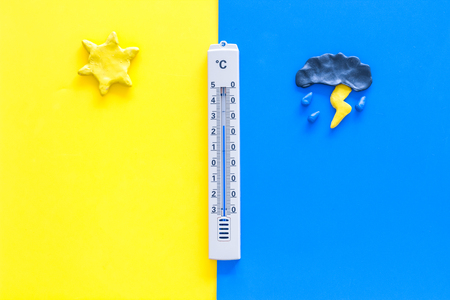Good and bad weather concept. Template for forecast. Sun vs cloud and lightening with rain on yellow and blue background top view copy spaceの写真素材