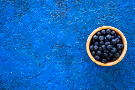 Fresh recently picked blueberries in bowl on blue background top view.の写真素材