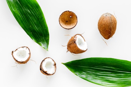 Tropical composition with coconut. Whole coconuts and coconut cut in half near palm leaves on white background top view.の写真素材