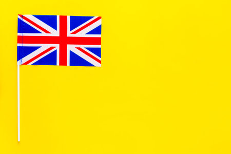 British flag concept. Small flag on yellow background top view space for text