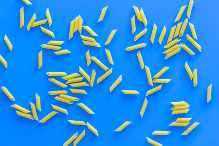Pasta background. Raw penne on blue background top view.の写真素材