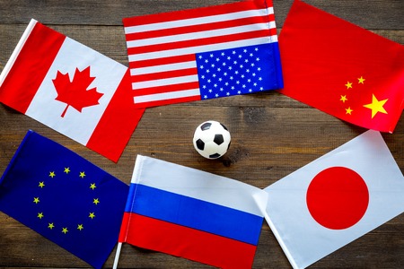 Football championship. American, Canadian, European, Japanese, China, Russian flags and football ball on dark wooden background top viewの写真素材