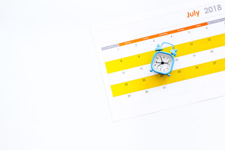 Deadline concept. Alarm clock on calendar on white background top view.