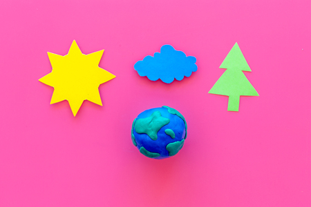 Environment protection concept. Plastiline symbol of planet Earth and sun, cloud, tree coutout on pink background top view.の写真素材