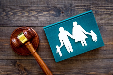 Family law, family right concept. Child-custody concept. Family with children cutout near court gavel on dark wooden background top view.の写真素材