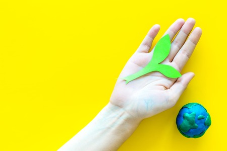 Planet, ecology. plastiline symbol of planet Earth globe and plant coutout on yellow background top view copy spaceの写真素材