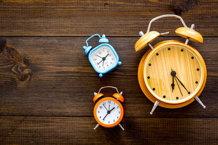Alarm clock for for waking up on dark wooden background top view.の写真素材