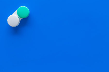 Contact lenses in container on blue background top view.