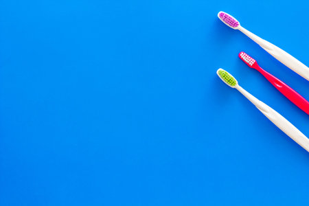 Clean teeth. Toothbrushes on blue background top view copy space