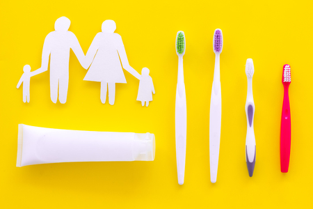Teeth care, dental care. Toothbrushes and tooth paste near family silhouette on yellow background top view.の写真素材