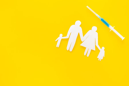 Vaccination for healthy family, vacctination of children. Flu. Syringe near family cutout on yellow...