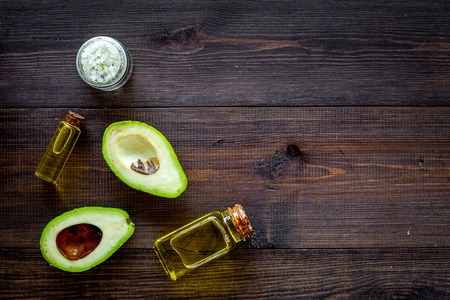 Organic cosmetics with natural ingredients. Avocado essential oil near half of avocado on dark wooden background top view space for textの写真素材