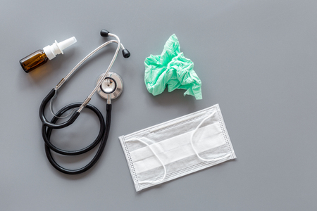 Flu drops. Running nose concept. Wrinkled napkin near stethoscope and face mask on grey background top view.の写真素材