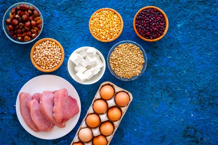 Food for sportsmen. Legumes, nuts, low-fat cheese, meet, eggs on blue background top view.の写真素材